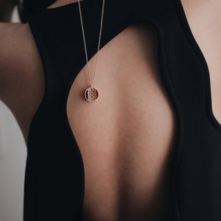 A woman in a black open back top wears a BIRKS diamond and gold circular necklace that hangs down her back, one of the pieces of fine jewelry by BIRKS that Perrara carries.