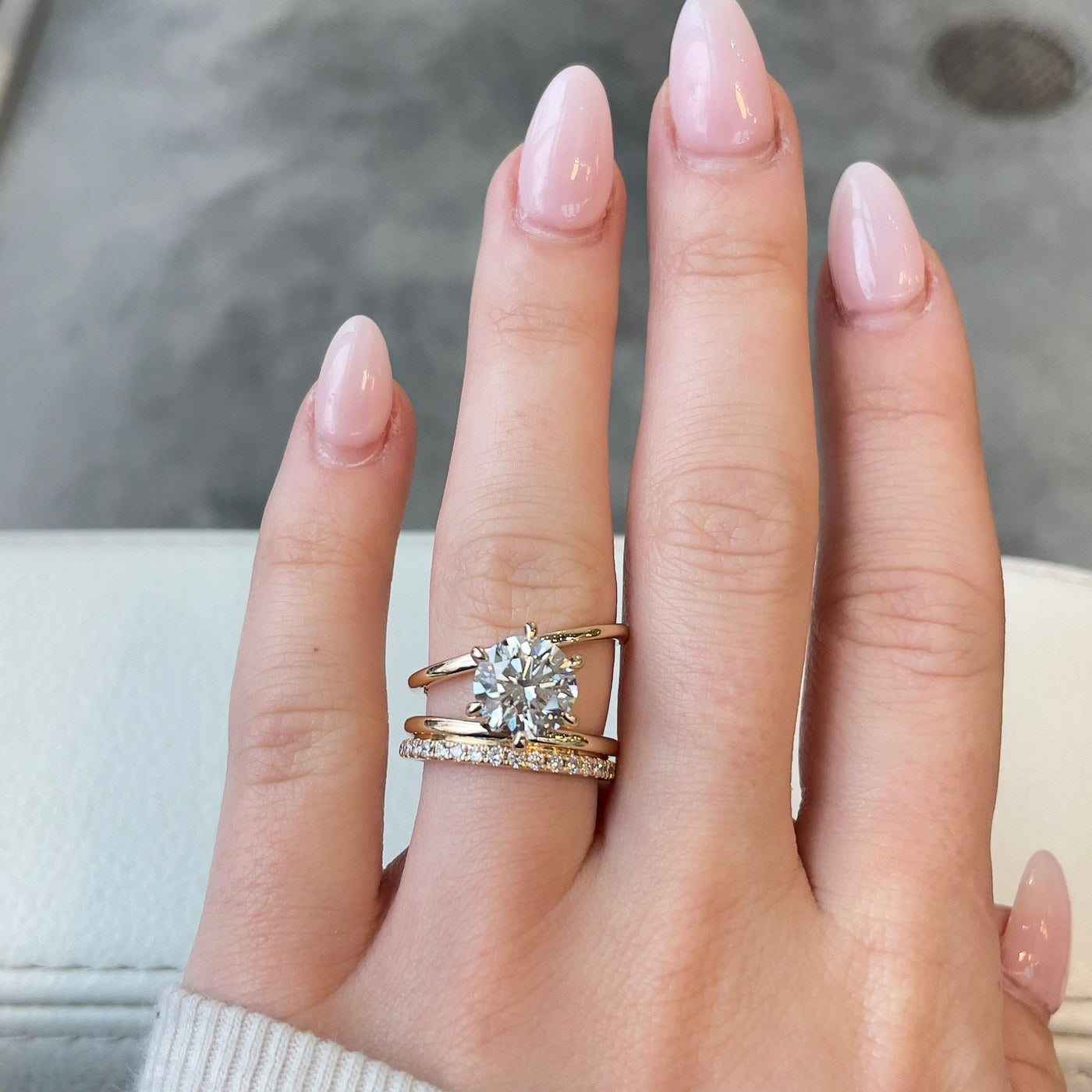 A custom round diamond engagement ring with a diamond band, on the hand