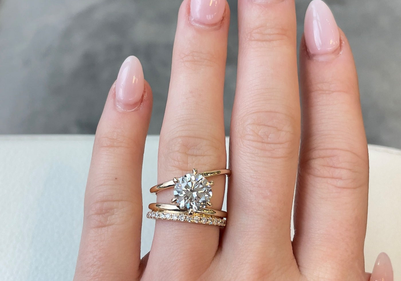 A custom round diamond engagement ring with a diamond band, on the hand