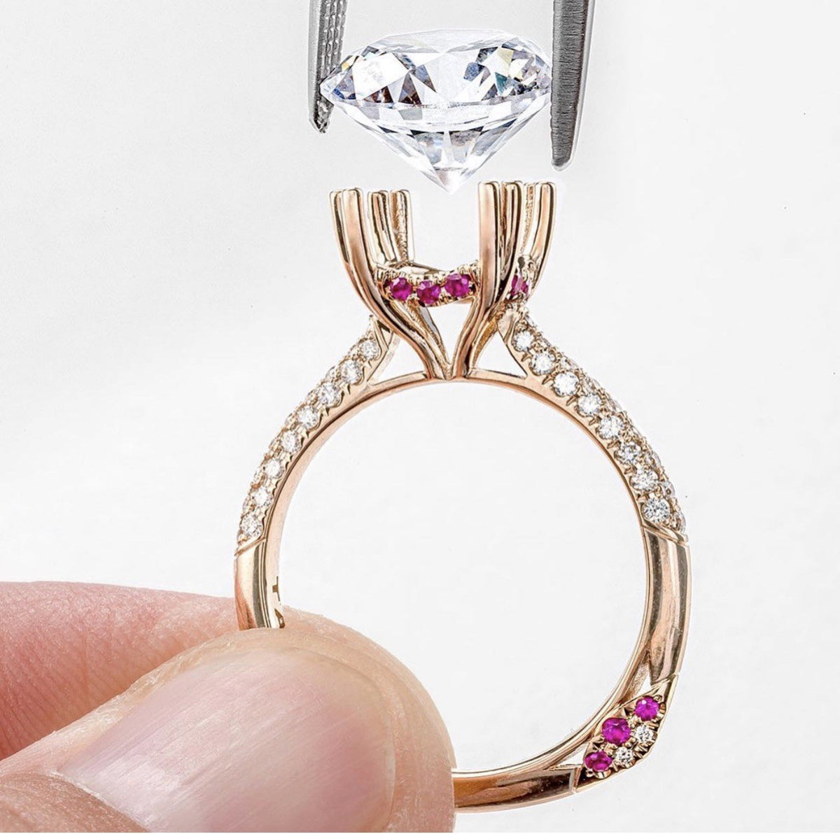 A Tacori engagement ring customized with pink sapphires, its center diamond held above the setting