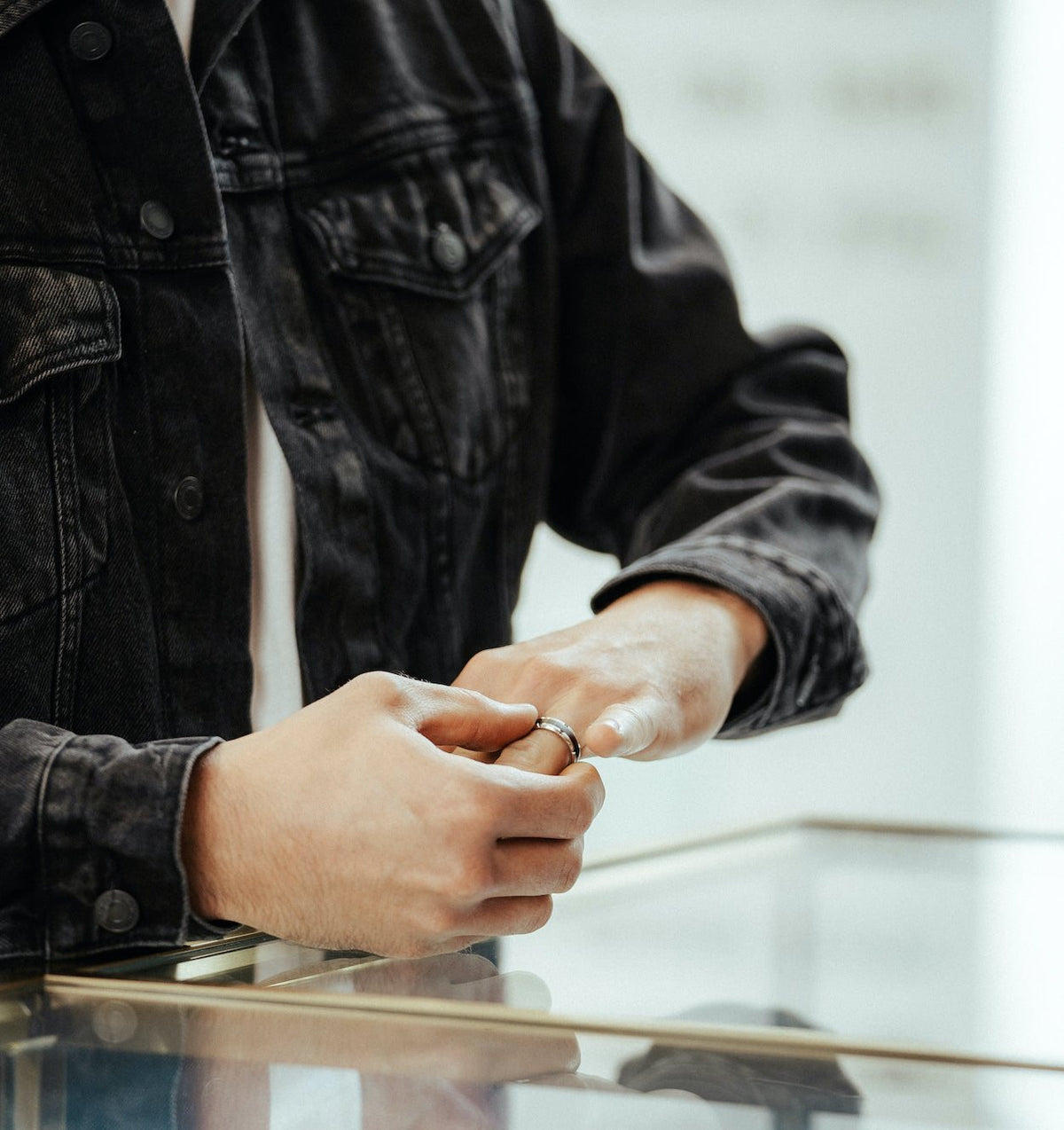Hands holding a ring over the glass case at Perrara