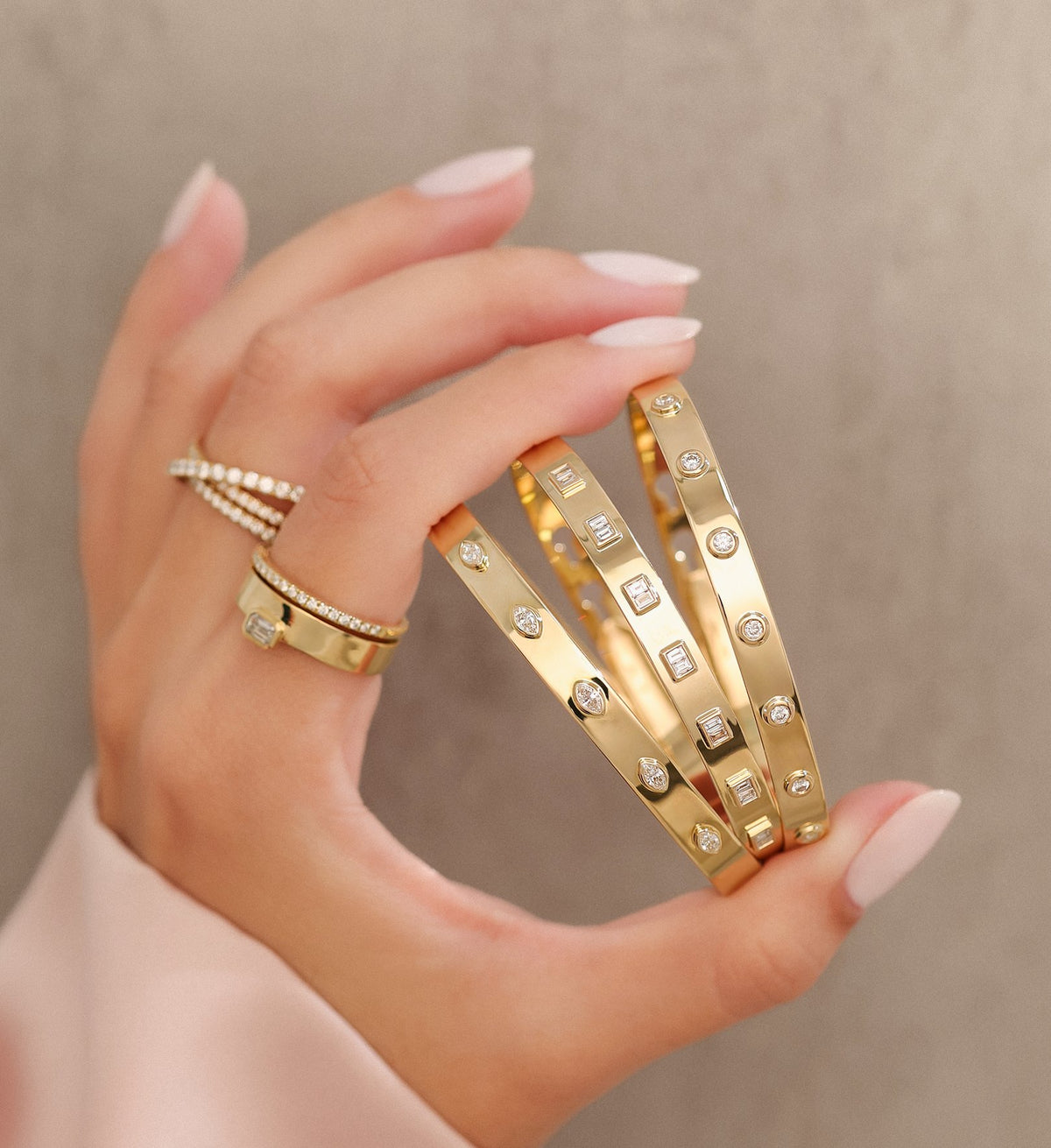 Shy Creation gold and diamond bangles held in one hand